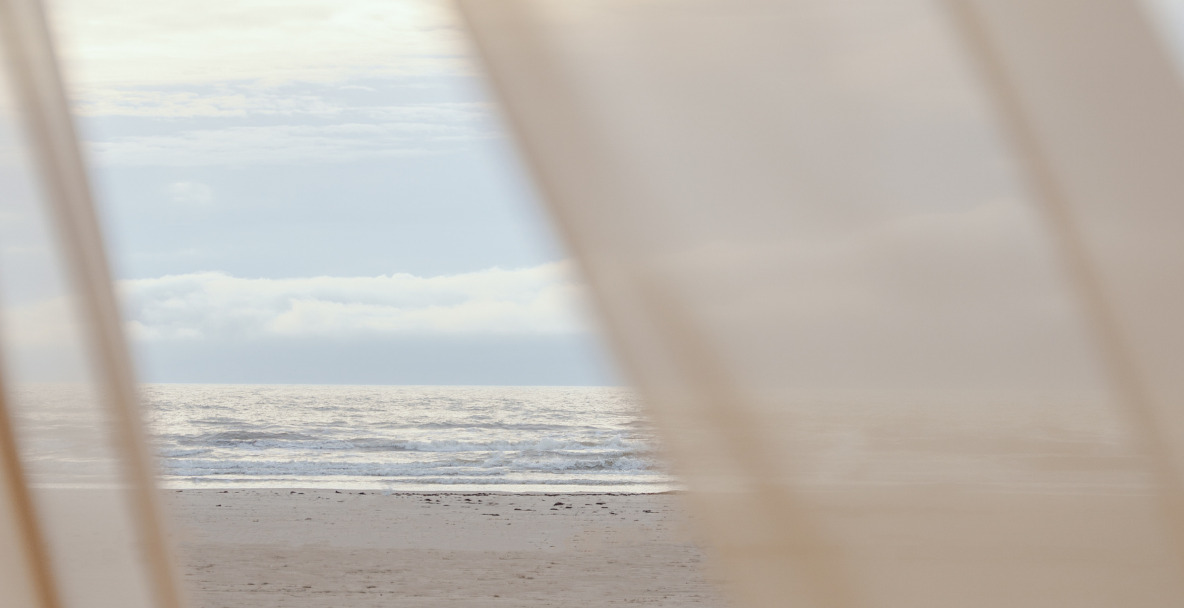Strand und Meer hinter einem hellen Vorhang